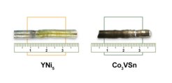 Two metallic rods, one labeled YNi₅ and the other Co₃VSn, displayed horizontally with rulers underneath to indicate their dimensions. Each rod exhibits distinct coloration and texture, suggesting differences in material composition.