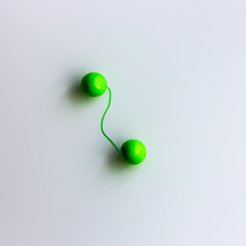 Two bright green spheres connected by a thin string, placed on a smooth white background.